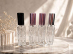 Four crystal perfume bottles with different colored caps on a marble surface.